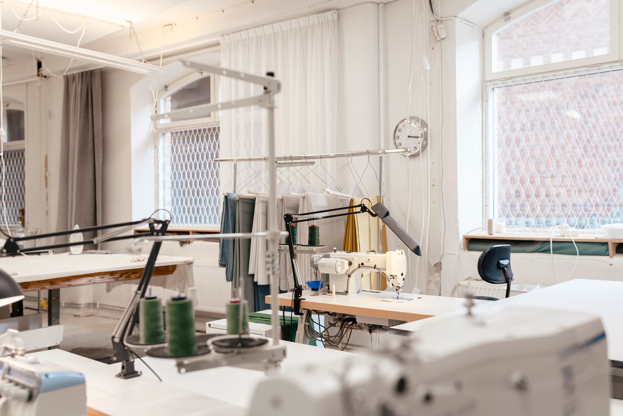 Bright clothing workspace with sewing machines and fabric tables